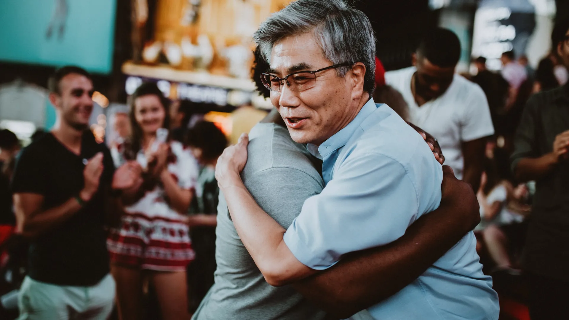 older asian man hugging an african american man in show of support